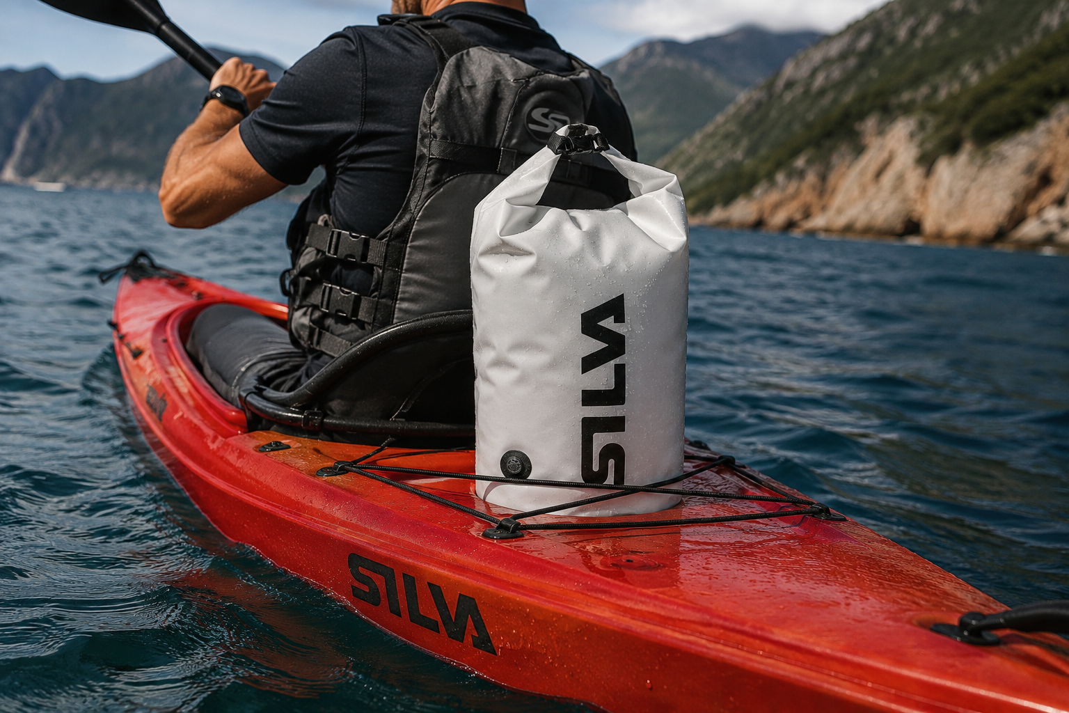 Silva TPU-V 48L compression dry bag secured to the deck of a red kayak on open water with mountains in the background