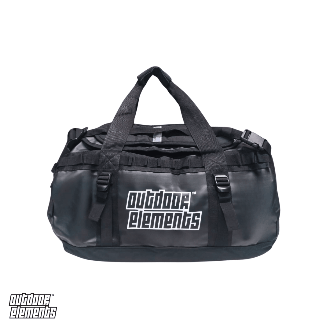A black Outdoor Elements duffel bag with dual top handles, multiple compression straps, against a plain white background.